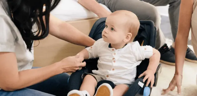A baby sitting in a stroller being examined by a woman