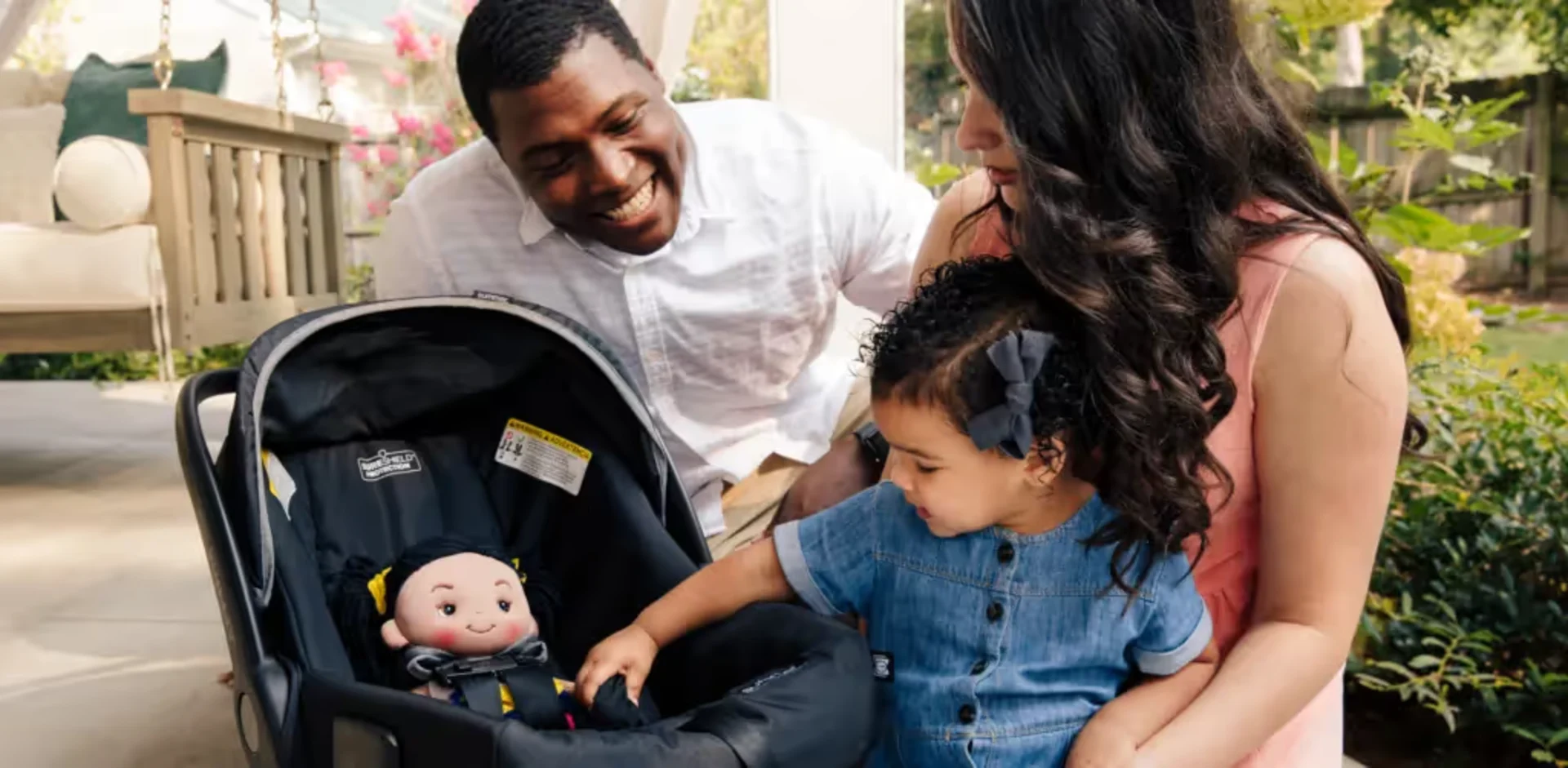 A man, woman and child looking at a doll in a stroller