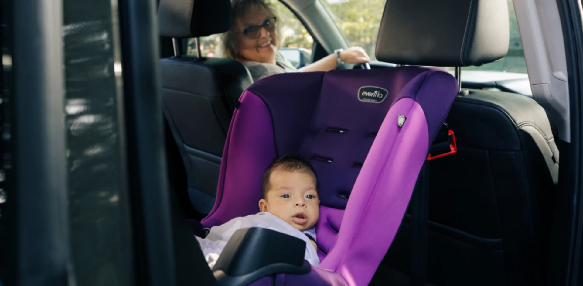 A baby in a car seat with a woman behind it
