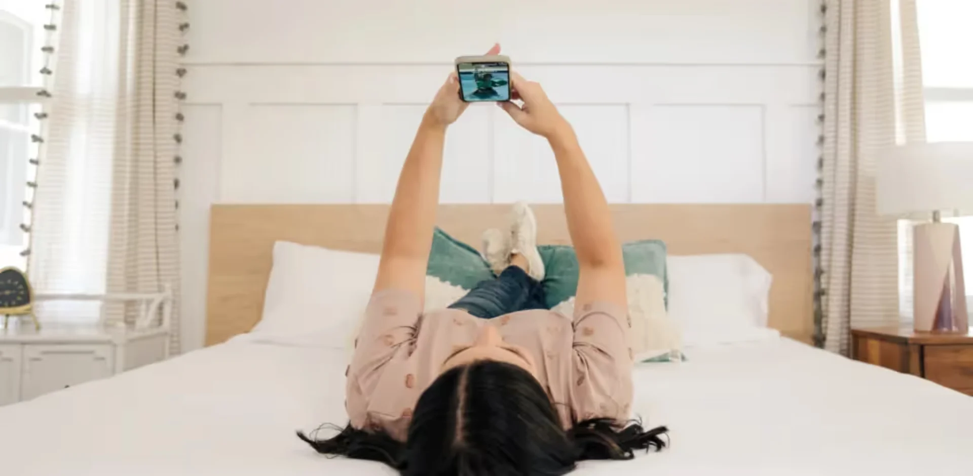 A person laying on a bed with a cell phone