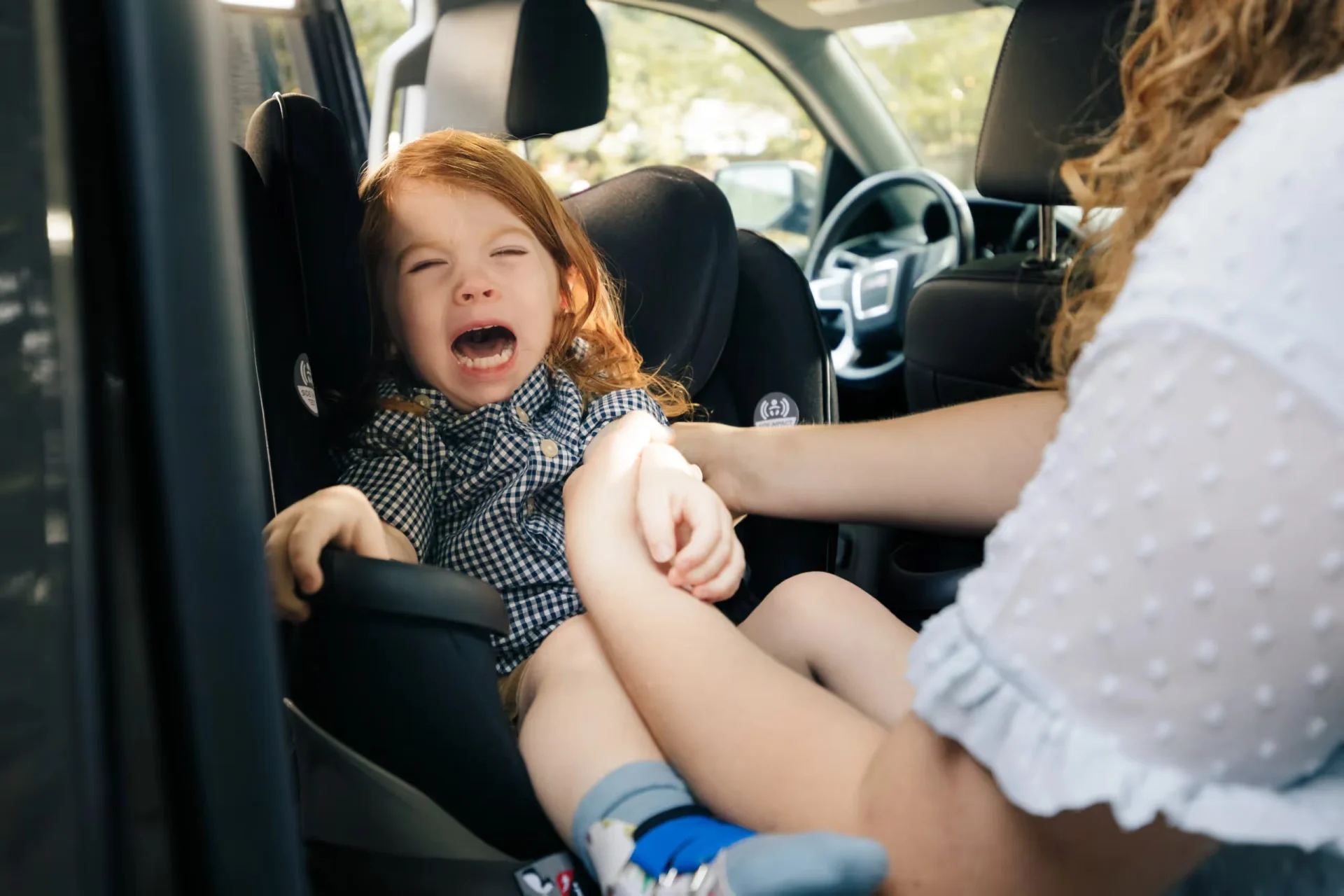 A little girl sitting in the back seat of a car