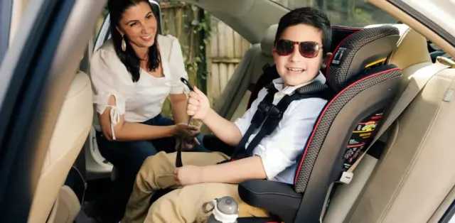 A woman sitting next to a child in a car seat