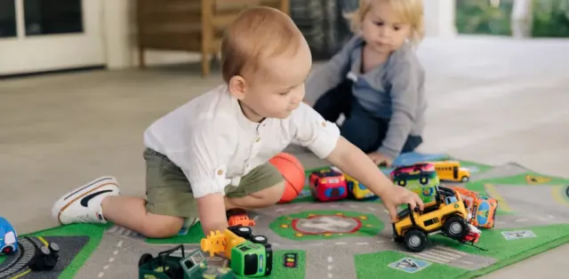 Two toddlers playing with toys on the floor