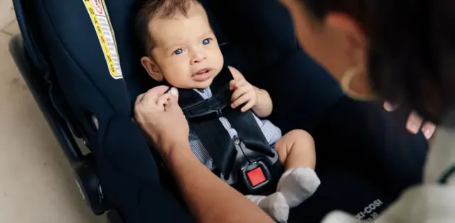 A woman holding a baby in a car seat
