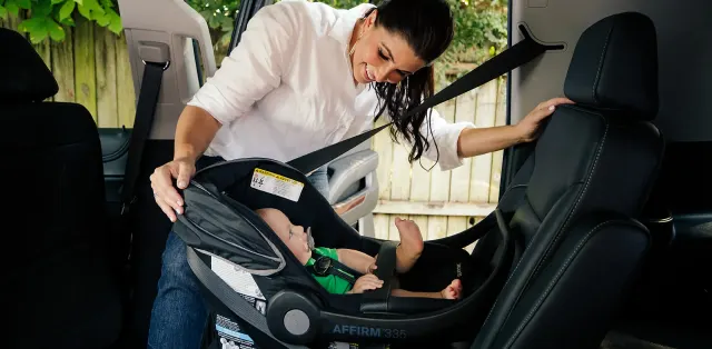 A woman putting a child in a car seat