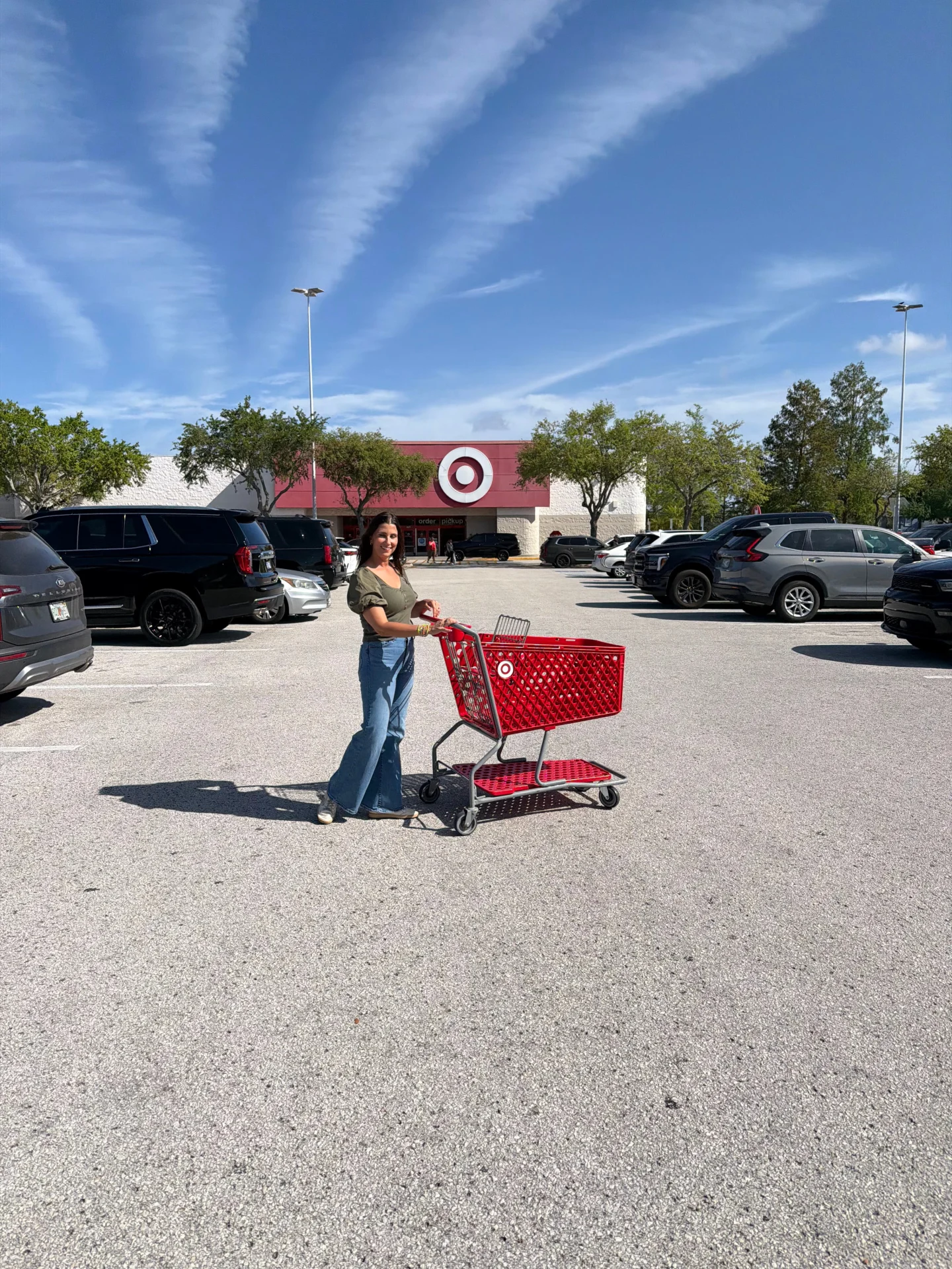 Woman with Target shopping cart full of car seats outside store entrance