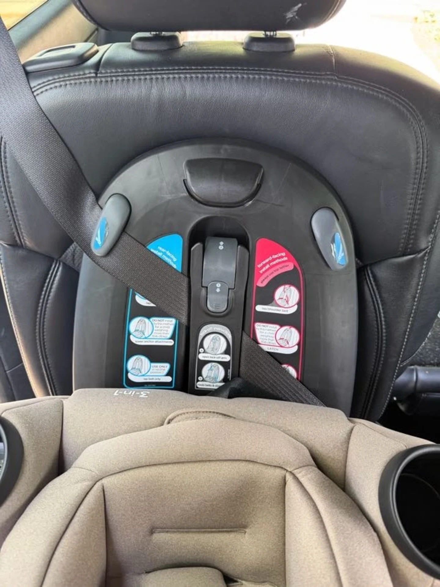 Joie Spin SI convertible car seat in matcha installed rear-facing in black leather car seat showing blue and red installation
