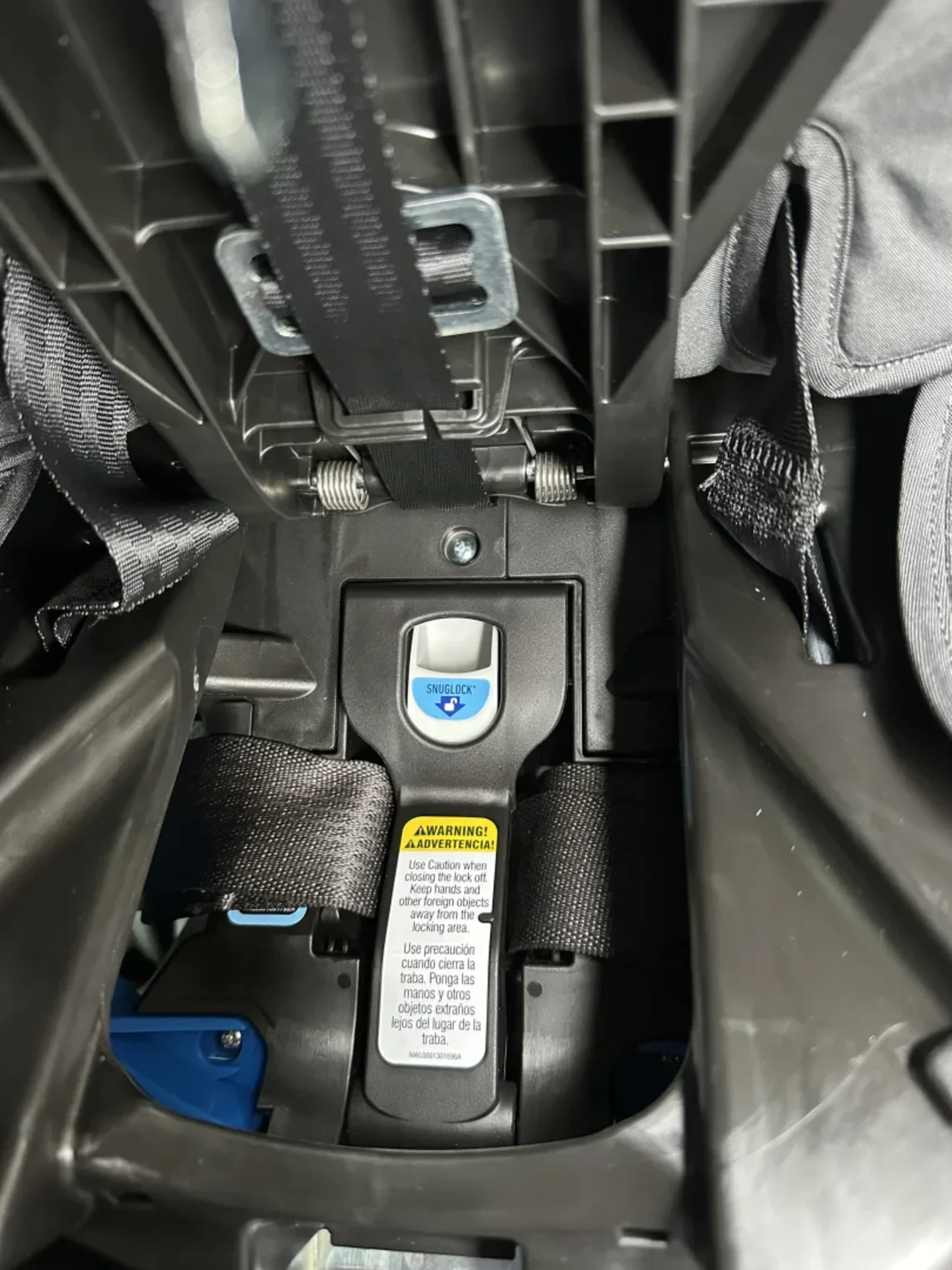 Graco Turn2Me car seat base with SnugLock seatbelt locking mechanism installed in vehicle rear seat with warning label visibl