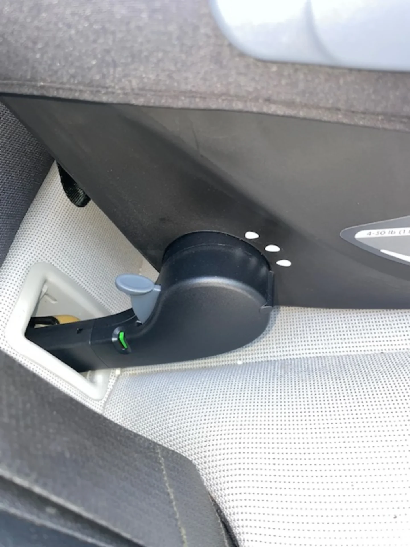 Close-up of Joie Mint car seat ISOFIX latch connector showing green indicator and release button beneath seat base