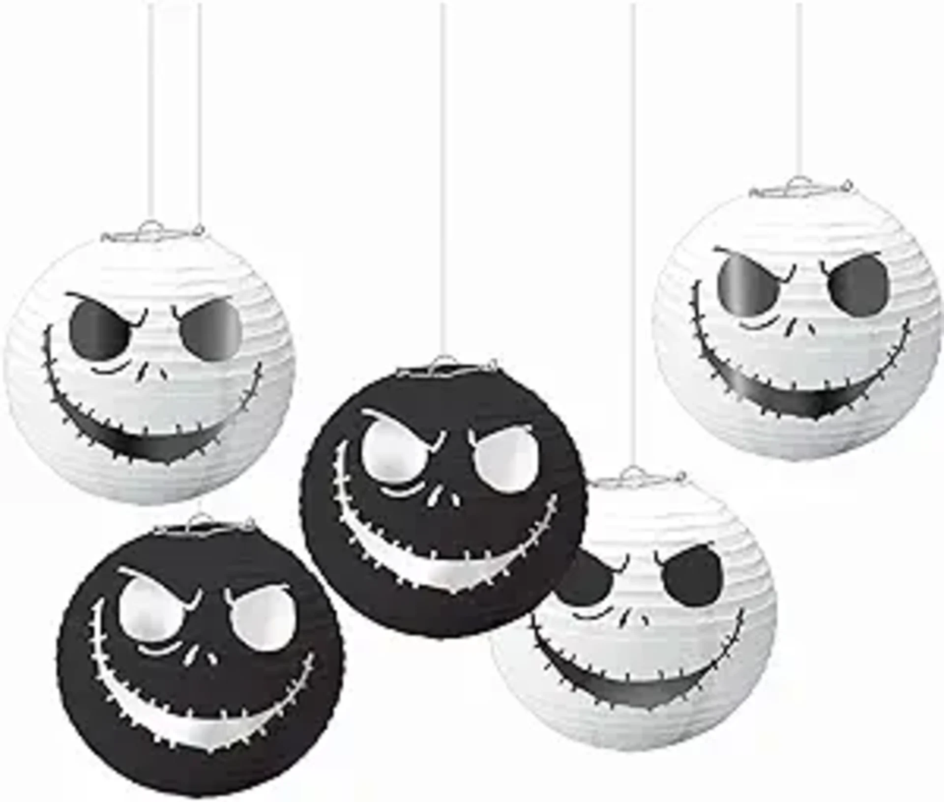 Five black and white Jack Skellington paper lanterns with evil grinning faces hanging from strings for Halloween party decor