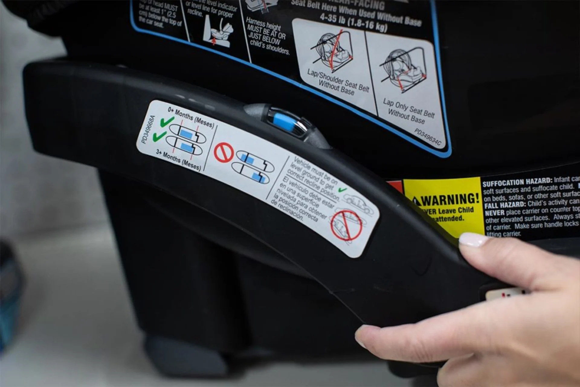 Close-up of infant car seat base showing recline level indicator sticker with age-based recline positions and bilingual safet