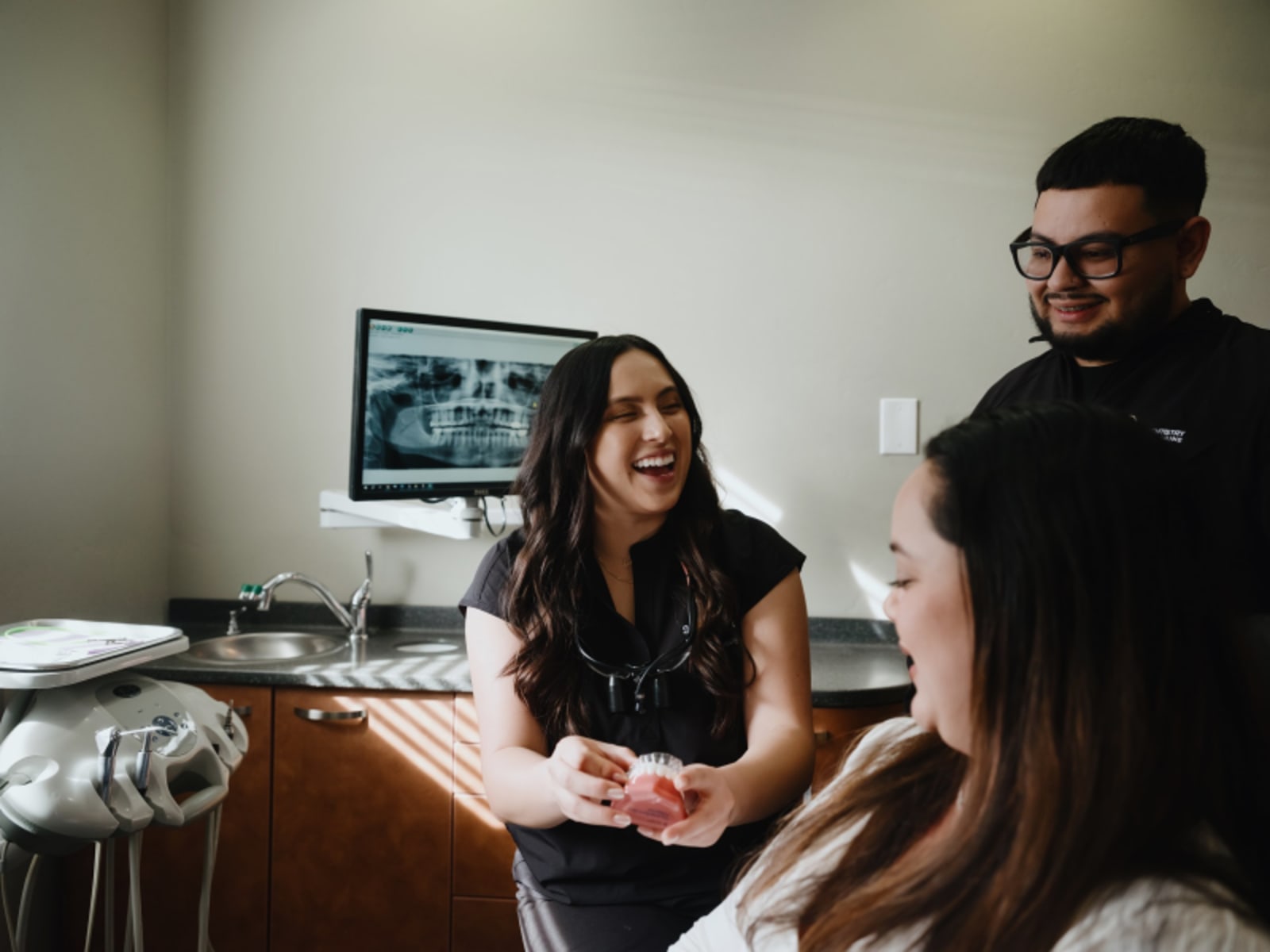 Dentist consulting with patient in clinical treatment room with dental equipment