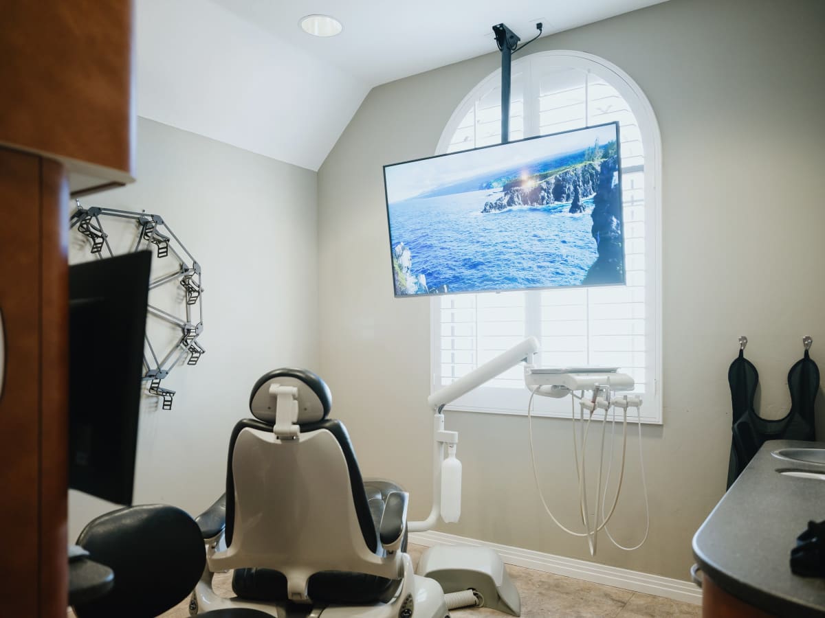 Modern dental operatory with monitor displaying patient education and sedation equipment visible.