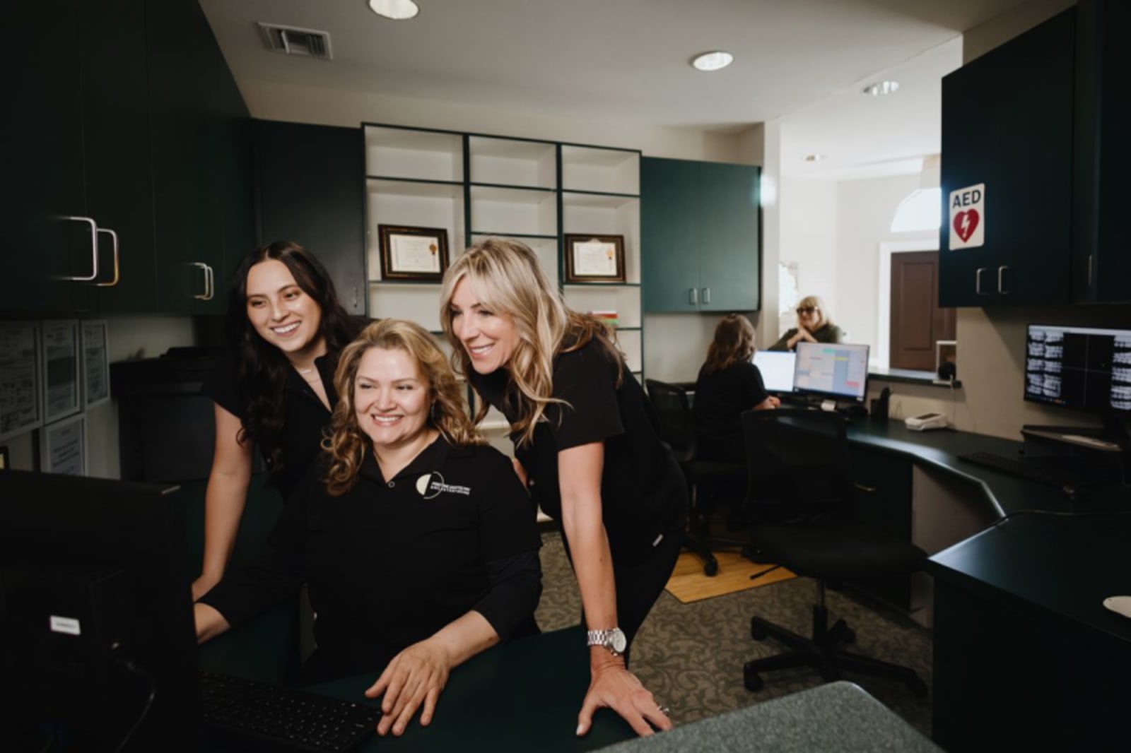 Four dental team members smile together in a modern dental office treatment area.