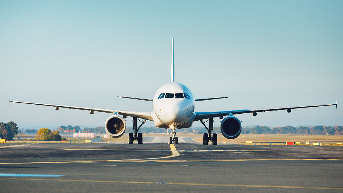 Front view of large commercial airplane on runway under clear sky at airport.
