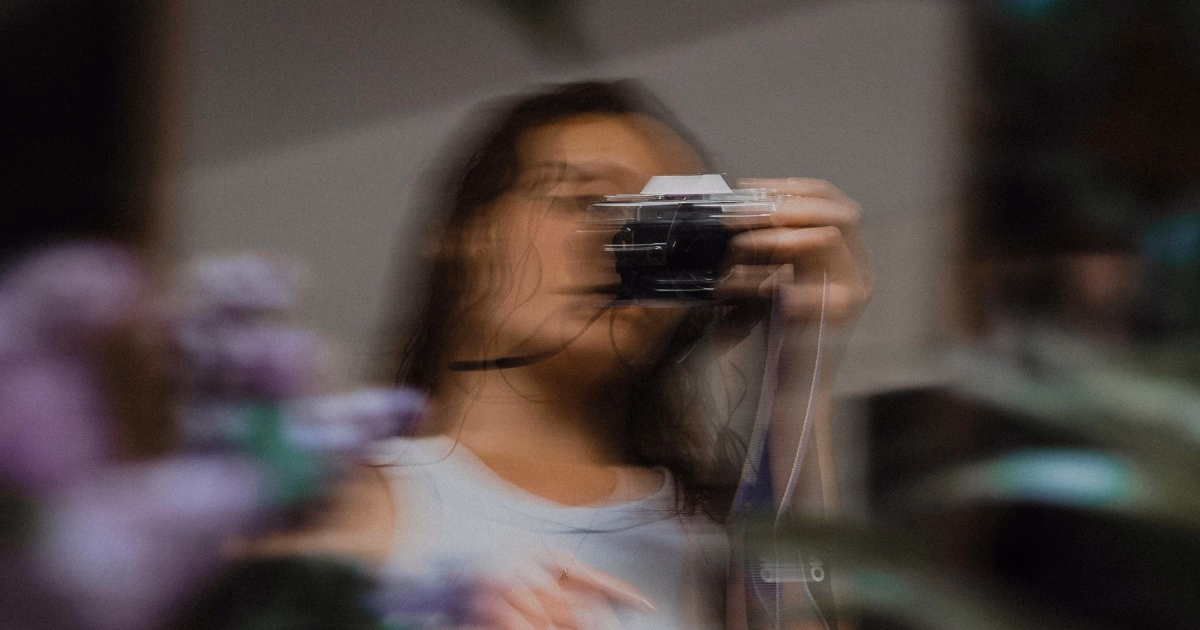 Social media manager taking photos for social media content creation using a camera to produce visual content for a brand.