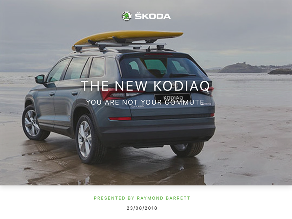 Rear-side view of a parked gray Škoda Kodiaq SUV on a wet sandy beach with a yellow surfboard mounted on the roof racks under an overcast sky.