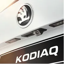 Close-up of the rear of a Skoda Kodiaq vehicle showing the Skoda logo, rear camera, and part of the license plate with 'KODIAQ' text.