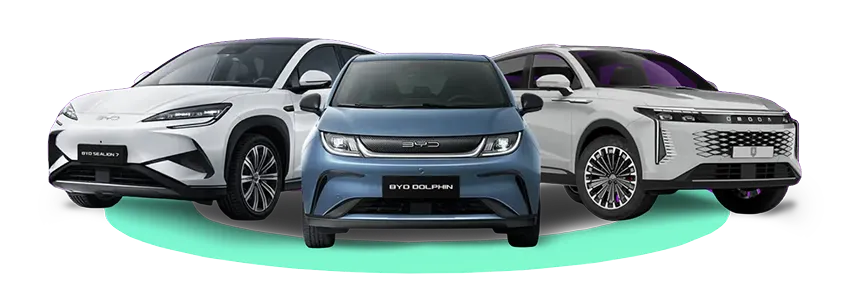 Front view of three modern BYD electric cars side by side on a light green surface: white BYD Seal on the left, blue BYD Dolphin in the center, and white BYD Atto 3 on the right.