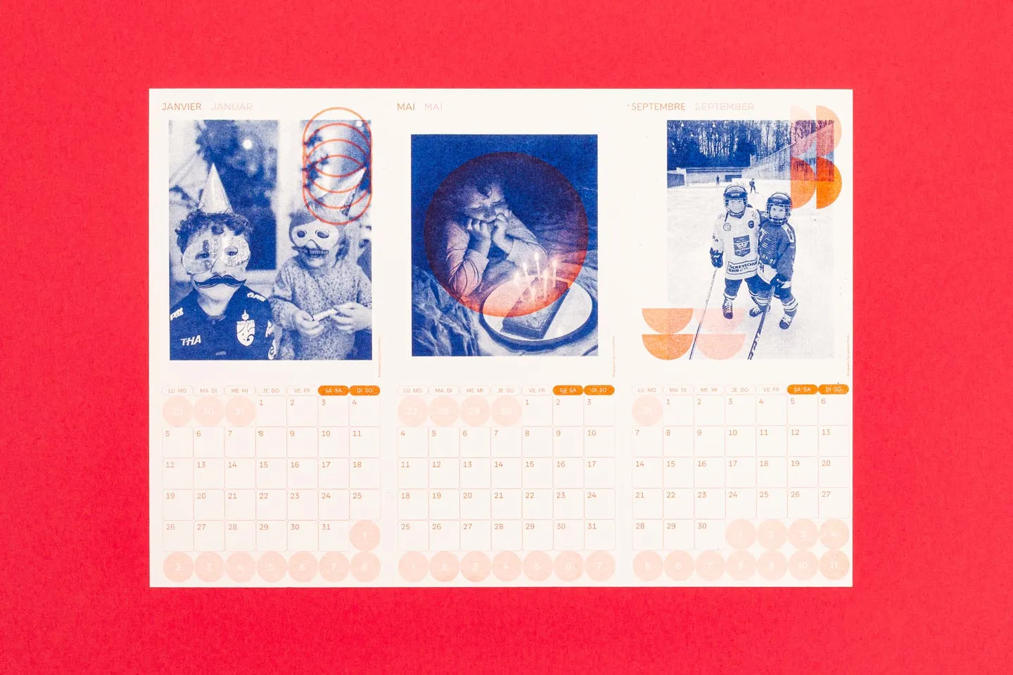 Ein bunter Kalender zeigt verspielte Bilder von Kindern mit Masken, beim Kuchenessen und beim Schlittschuhlaufen, umgeben von lebhaften geometrischen Formen. Der Kalender wurde im Risographieverfahren gedruckt.