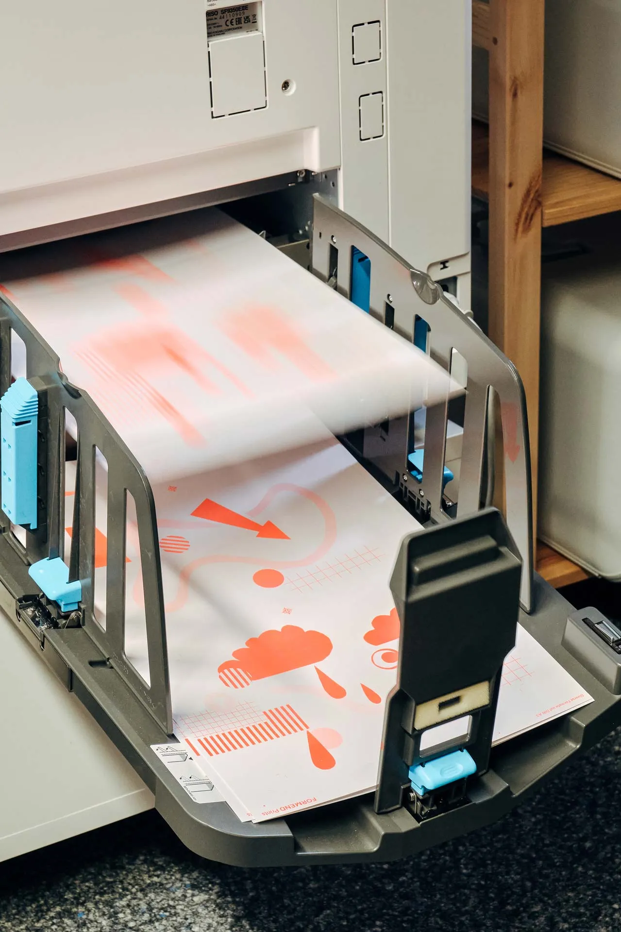 Risographie-Druck bei Formend: Frisch gedruckte Printbögen in leuchtenden Farben laufen aus dem Riso-Drucker.