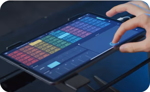 Person using the Remixlive app on a tablet, showing a grid of colorful sound pads for triggering loops and samples. The app interface includes a touch-sensitive XY pad for real-time effects control, demonstrating its capabilities for live music performance and remixing.