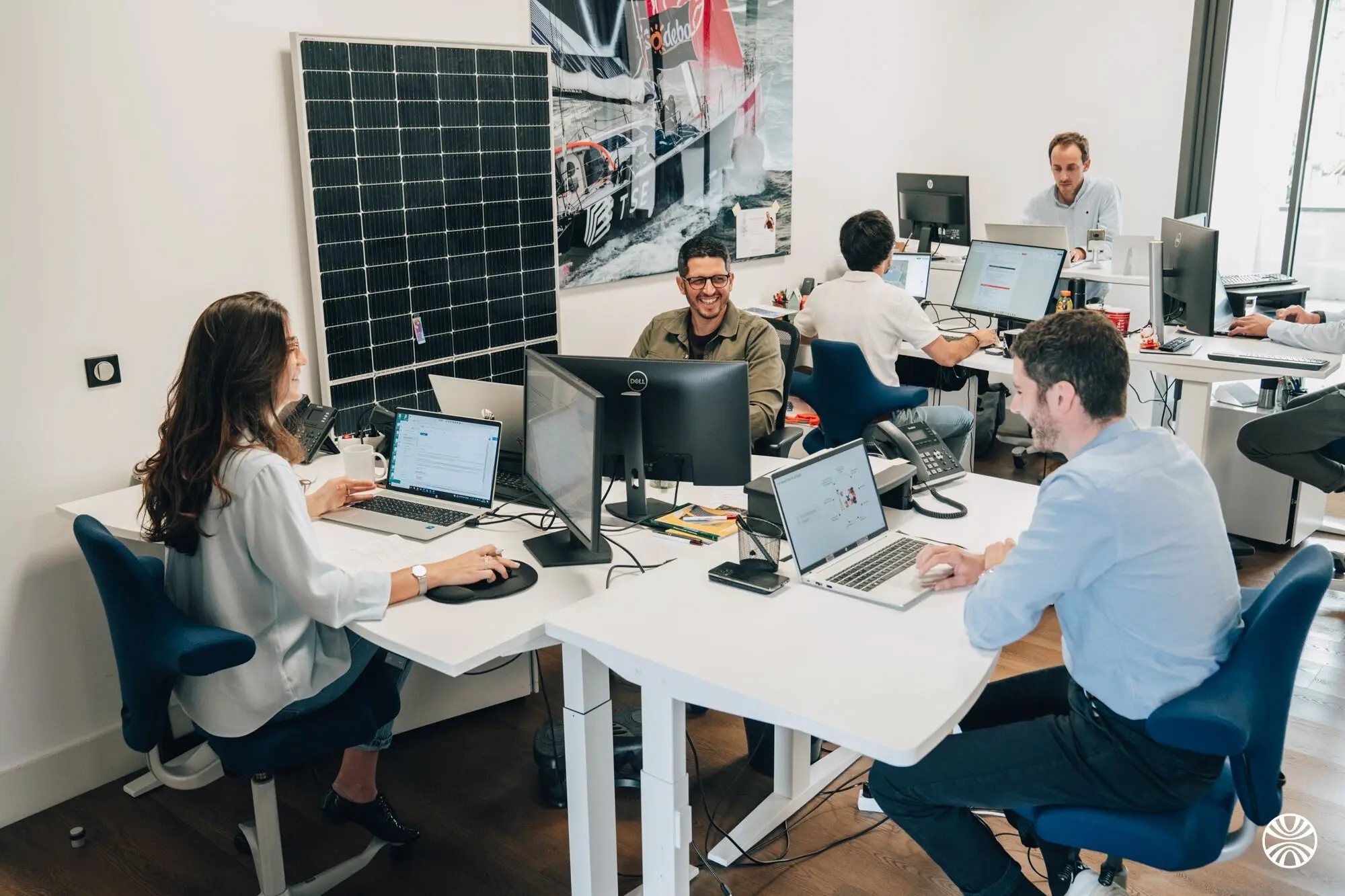 Collaborateurs TSE assis à leur bureau devant leur ordinateur travaillant dans une ambiance heureuse et conviviale.