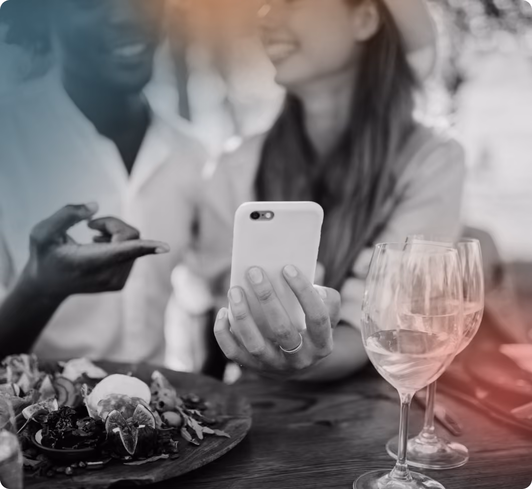 Woman holding phone and showing it to man on dinner table