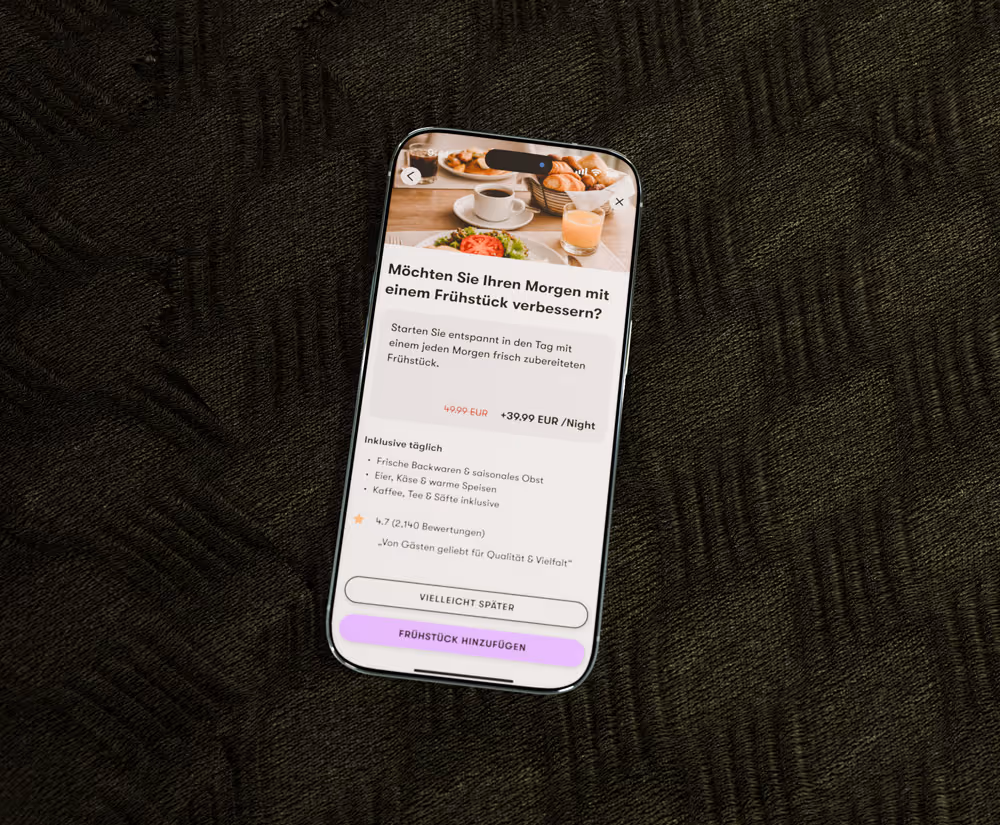 Smartphone auf dunklem Stoff mit Frühstücksangebot und Preisangabe in einer App auf dem Bildschirm.