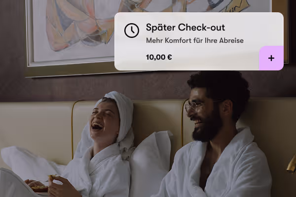 Paar in Bademänteln lacht zusammen im Bett, darüber Textbox für späten Check-out und Preis.