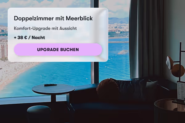 Zimmer mit Sofa und Tisch und Meerblick durch großes Fenster an einem sonnigen Tag.
