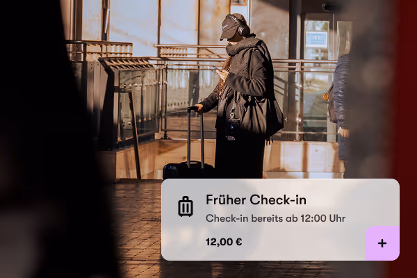 Person mit Koffer und Handy vor hell beleuchtetem Glasgeländer an einem Check-in-Ort.