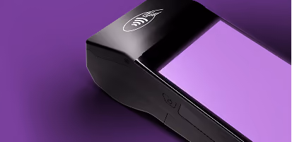 Nahaufnahme eines schwarzen Kartenterminals mit Kontaktlos-Symbol auf violettem Hintergrund.