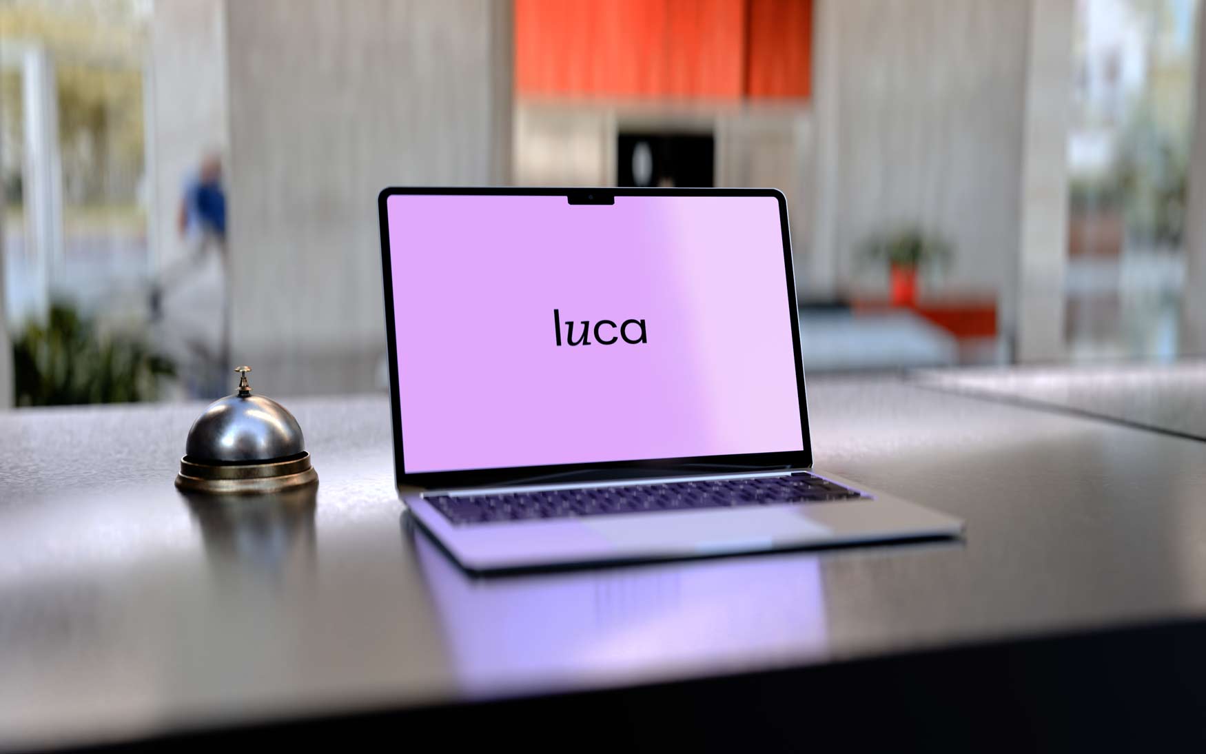 Modern hotel check-in with luca's digital hospitality solution: A laptop with luca branding sits on a reception desk next to a hotel bell in a stylish hotel lobby. The image symbolizes digital guest communication, hotel software, contactless service, and innovative technologies for the hotel industry.