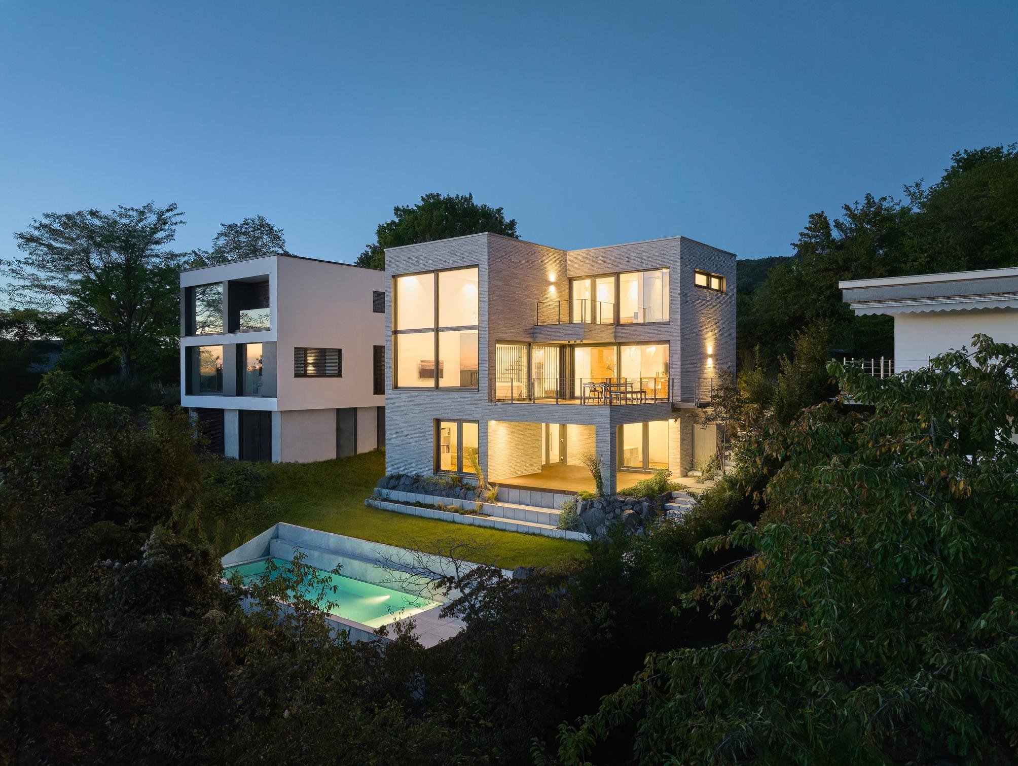 view at a modern house by night with a pool in the garden
