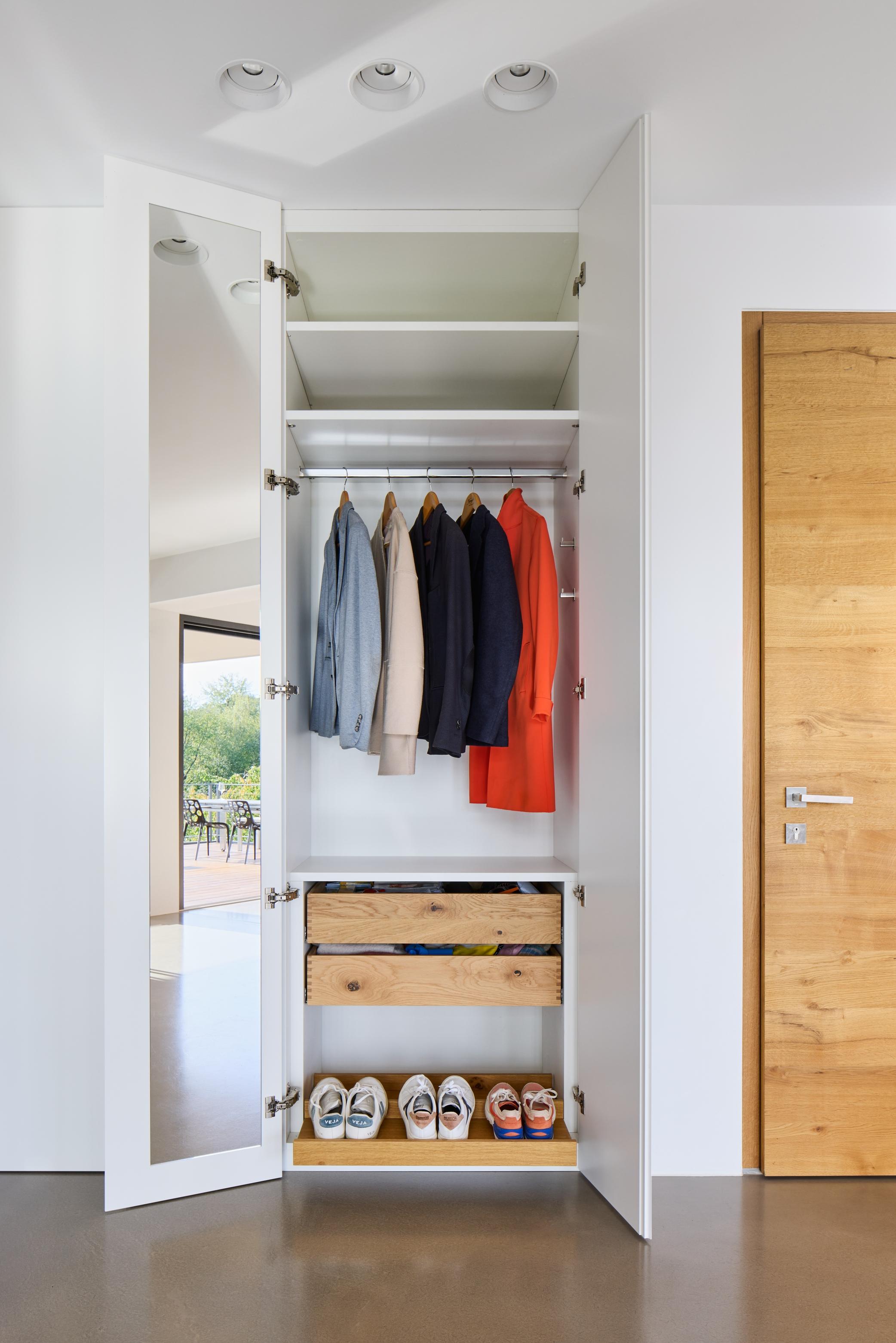 there is a closet with a shelf and a door with clothes