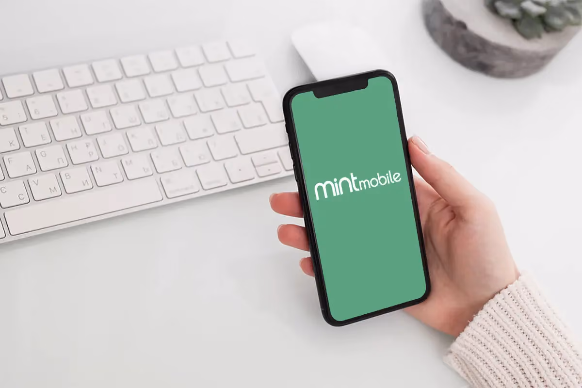 Hand holding phone with mint mobile logo on the screen