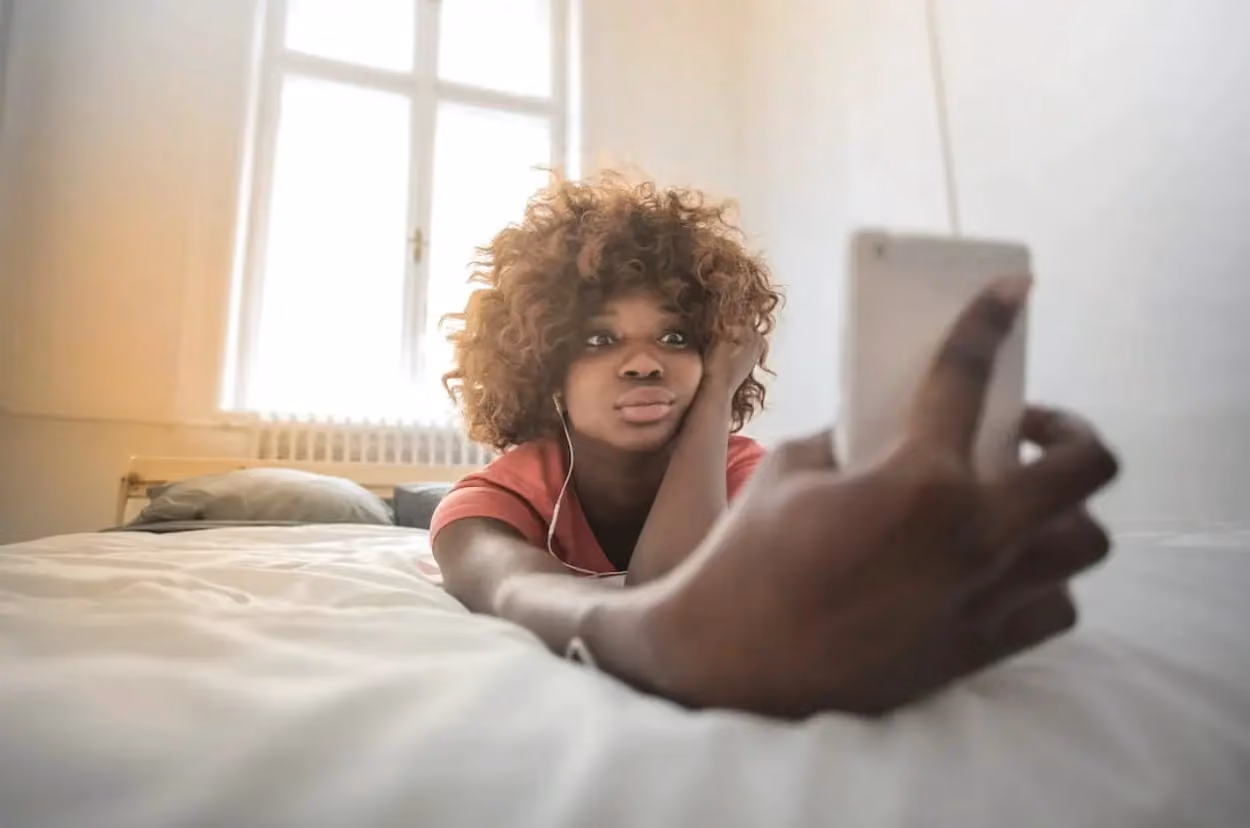 a person lying on a bed with headphones and a phone