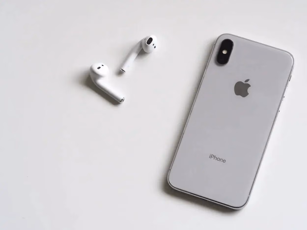 an iphone and airpods on a white surface