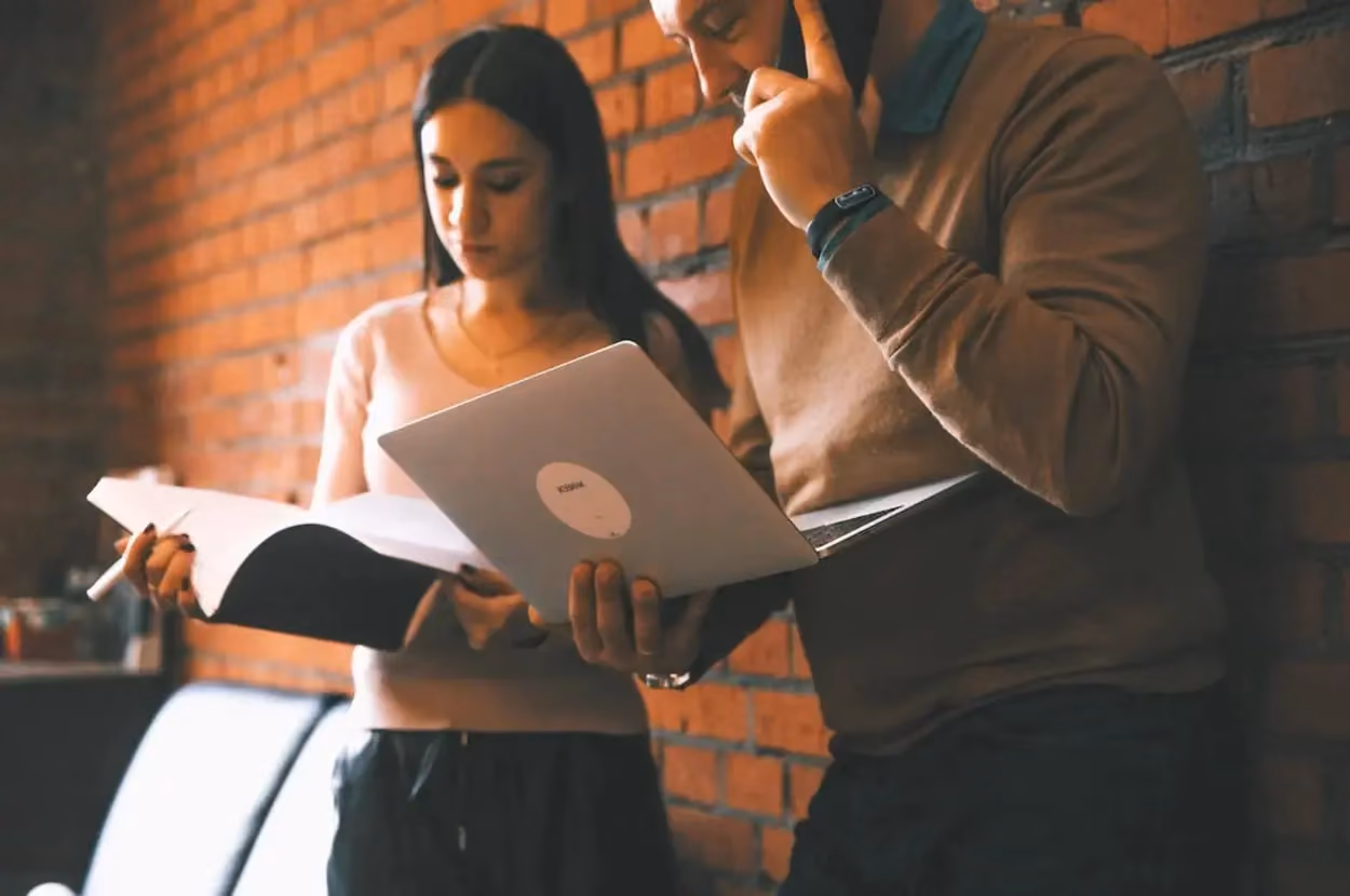 a man and woman standing next to a brick wall