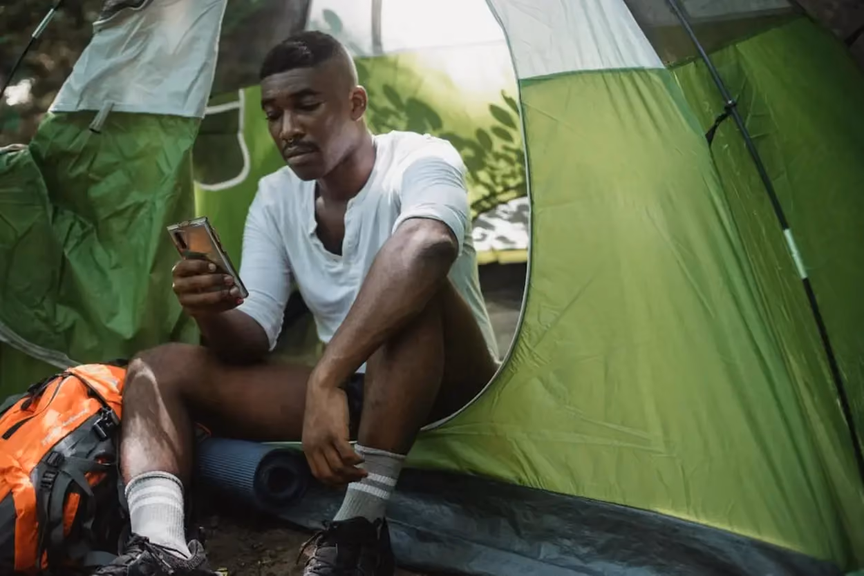 a person sitting in a tent looking at his phone