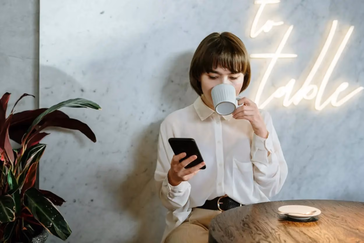a person drinking coffee and using a phone