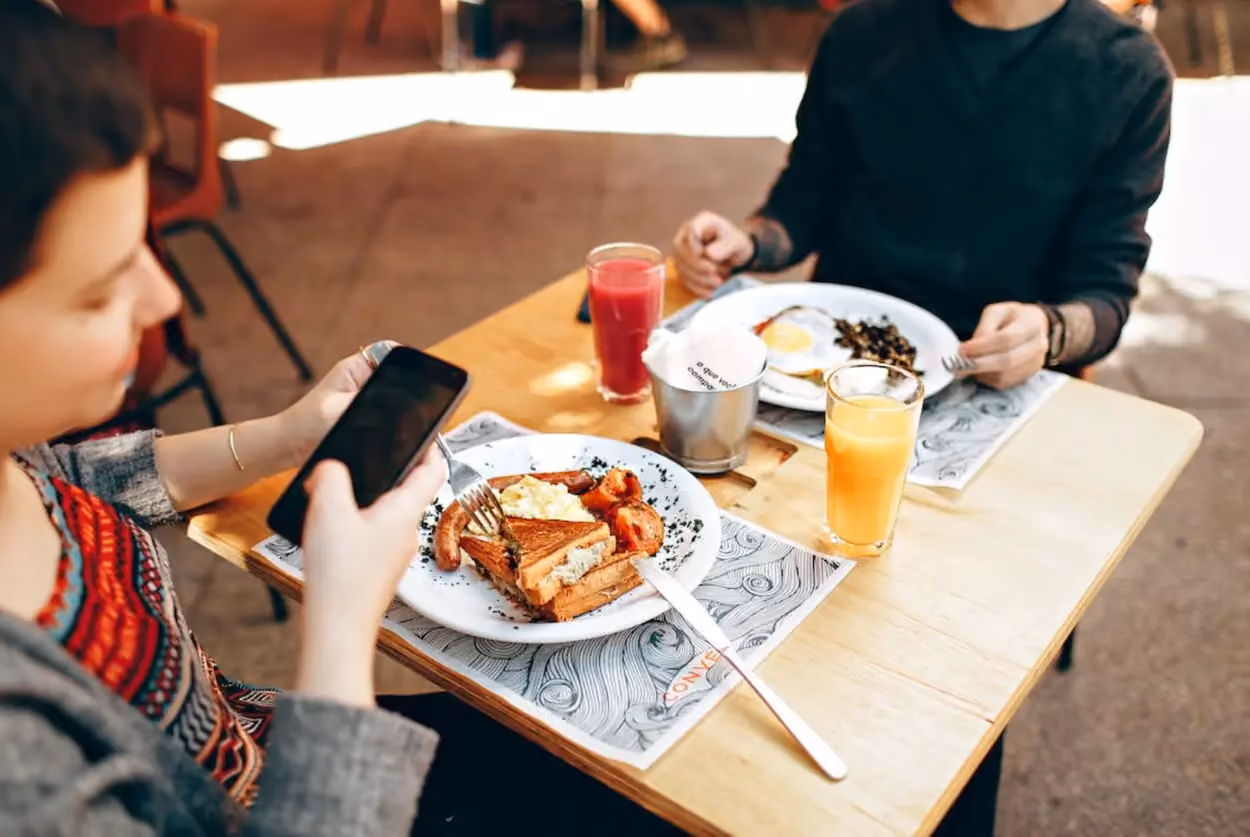 a person holding a phone while eating food