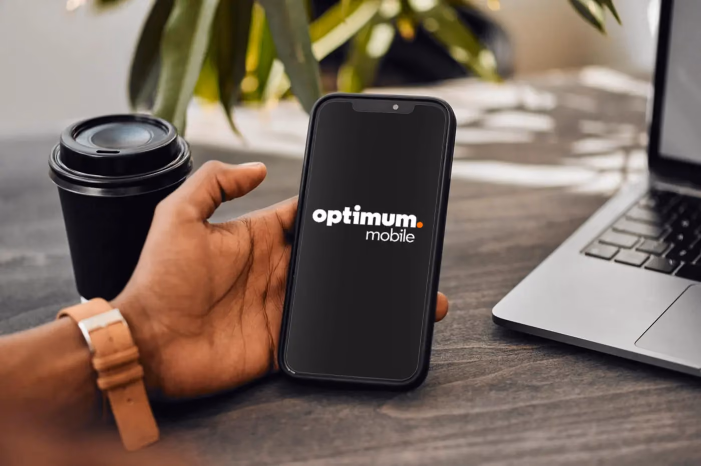 Hand holding phone with optimum mobile logo on the screen