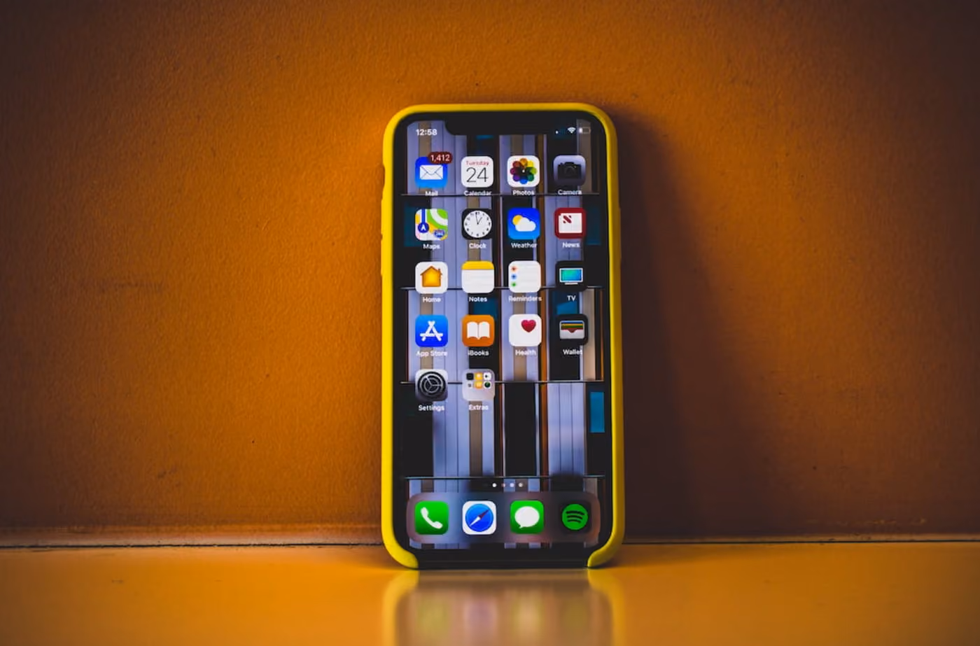 An iPhone rests on a table, set against a vibrant yellow background, showcasing its sleek design and modern aesthetics.