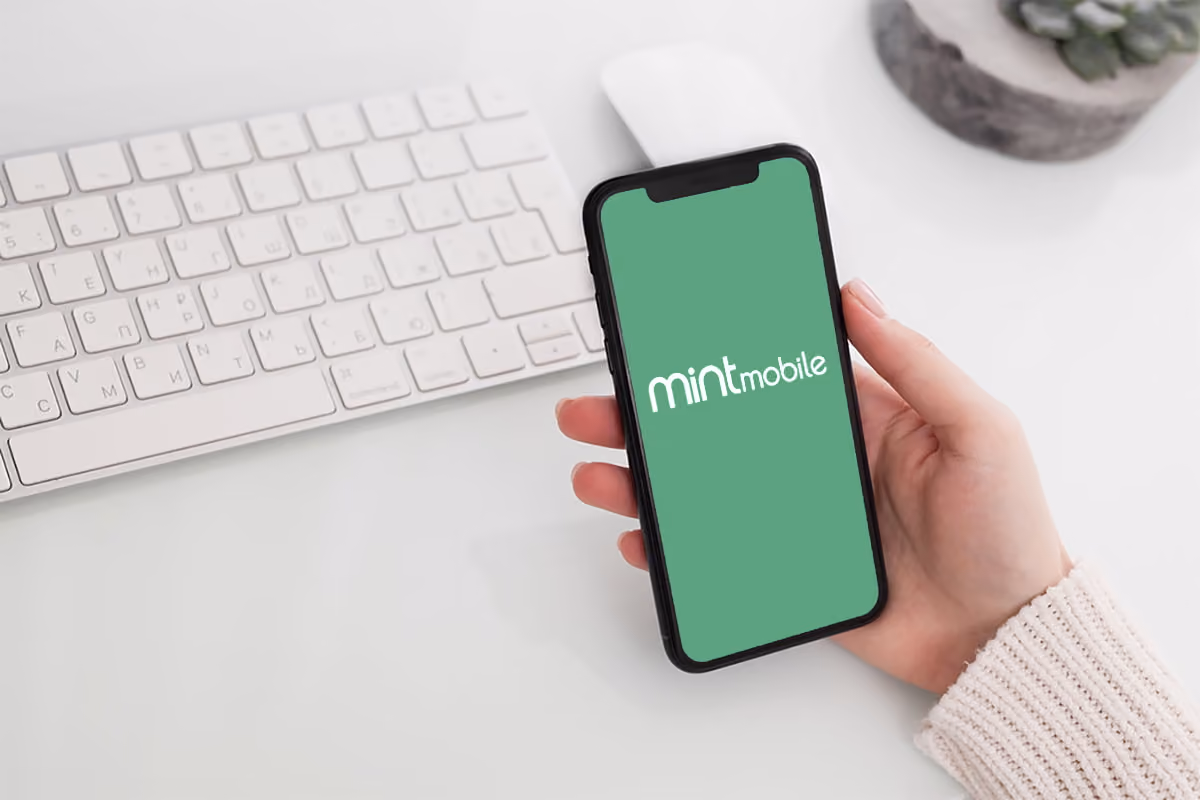 Hand holding phone with mint mobile logo on the screen