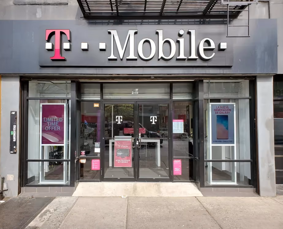 A T-Mobile storefront showcasing promotional posters and offers, with glass doors and a recognizable magenta-themed design.