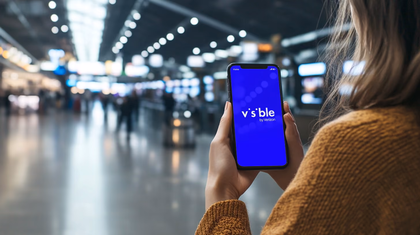 A person holding iphone with Visible Wireless logo on the screen