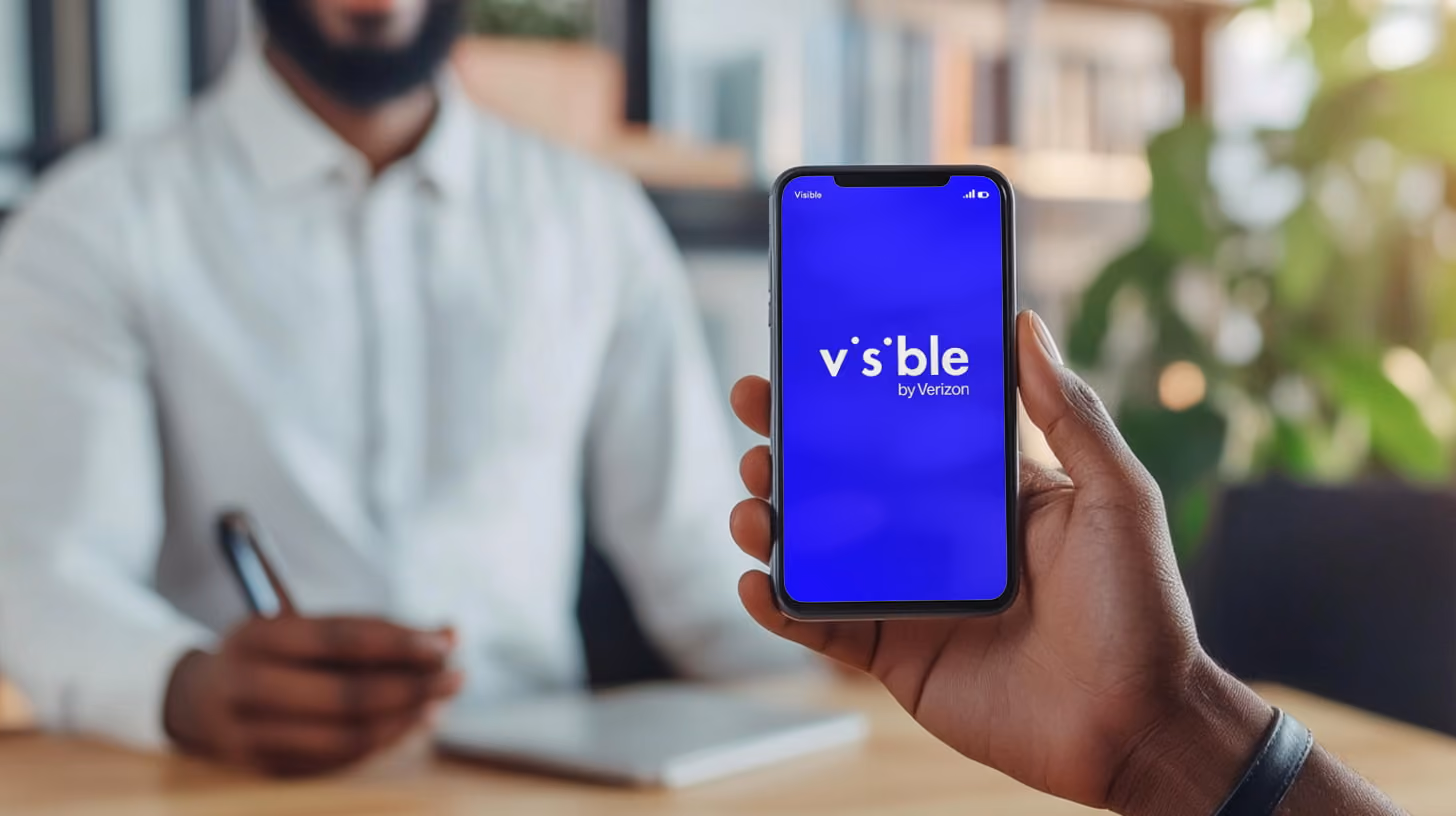 A person holding iphone with Visible Wireless logo on the screen