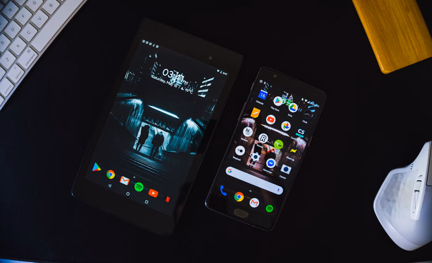 Two smartphones placed on a desk beside a keyboard, showcasing a modern workspace setup with technology at hand.
